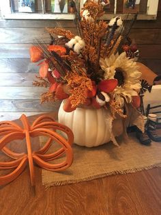 an arrangement of flowers in a white pumpkin on a table