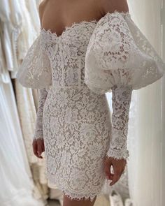 a woman in a white lace dress looking at her reflection