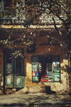 an old building with green shutters on the front and side windows that are open