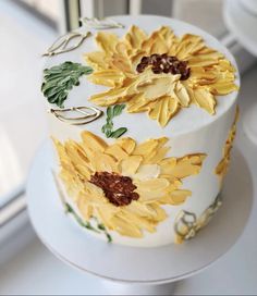 a cake decorated with sunflowers on top of a white countertop next to a window