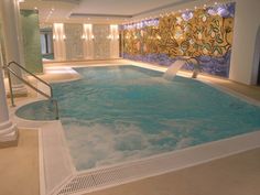 a large indoor swimming pool with an in - ground slider and water features painted on the wall