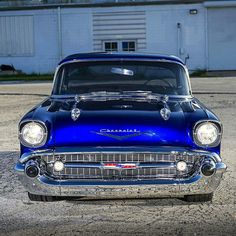 an old blue car parked in front of a building