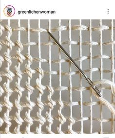 an image of a knitting needle on the side of a piece of cloth with white yarn