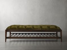 a bench with a green cushion on it in front of a white wall and floor