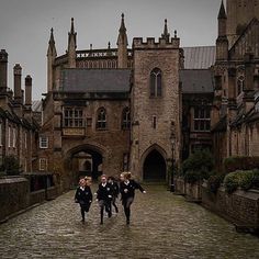 three children are running down an old cobblestone street in front of a castle