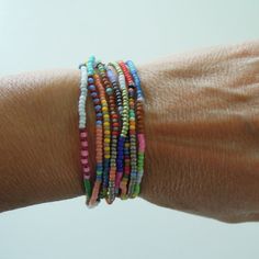 a woman's arm with several bracelets on it, including multicolored beads