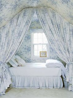 there is a white bed in the room with curtains on both sides and a window above it