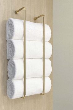 four white towels are hanging on a gold towel rack