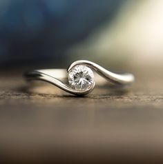 a diamond ring sitting on top of a wooden table next to a blurry background