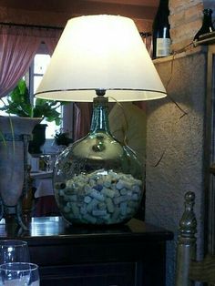 a lamp that is sitting on top of a table next to a vase with rocks in it