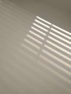 the sun is shining through the window blinds in this room with white walls and flooring