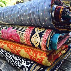 a stack of colorful fabrics sitting on top of a wooden table