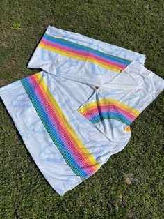 two pieces of cloth laying on top of the grass with rainbows painted on them