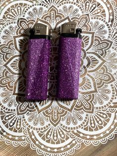 two purple glitter lighters sitting on top of a wooden table