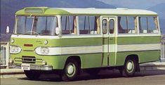 an old green bus is parked on the side of the road with mountains in the background