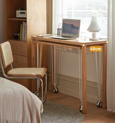 a laptop computer sitting on top of a wooden desk next to a bed in a bedroom