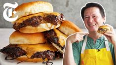 a man is holding up a hamburger in front of his face and the buns stacked on top of him