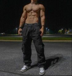 a shirtless man standing in the middle of a parking lot at night with no shirt on