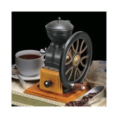 a coffee grinder sitting on top of a table next to a cup of coffee