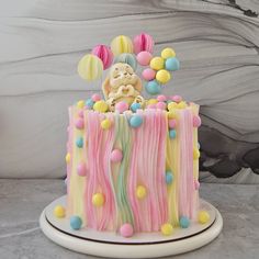 a cake decorated with pastel icing and balloons