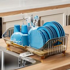 a dish rack filled with blue plates and silverware on top of a kitchen counter