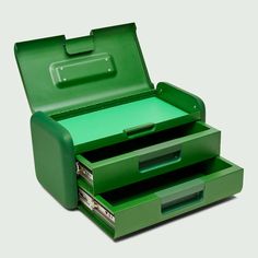 an open green briefcase sitting on top of a white table next to another box with two drawers