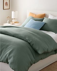 a bed with green sheets and blue pillows