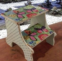 a small wooden bench sitting on top of a hard wood floor next to plants and rocks