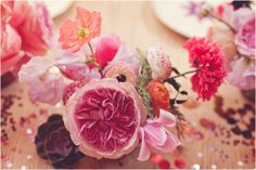 pink and red flowers are sitting on a table with confetti sprinkles