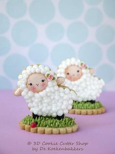 there are two cookies shaped like sheeps on the grass with flowers in their hair