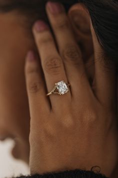 a close up of a person's hand with a diamond ring on their finger