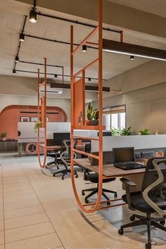 an office with multiple desks and chairs in the center, along with hanging planters