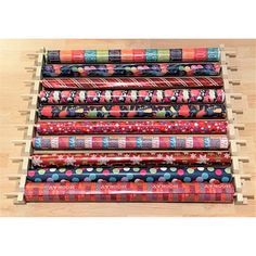 six rolls of wrapping paper are stacked on a wooden rack in front of a wood floor