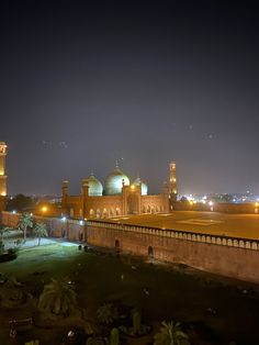 a large building with many lights on it's sides and grass in the foreground