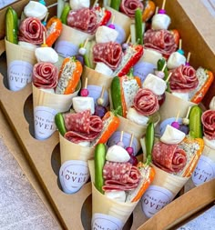 an open box filled with different types of appetizers and dips on sticks