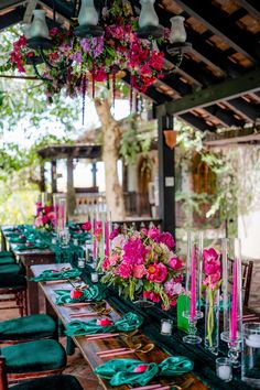 a long table is set up with green napkins, pink flowers and candles on it