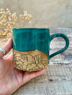 a hand holding a green and brown coffee mug