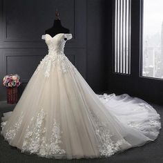 a wedding dress on display in front of a window with cityscape behind it