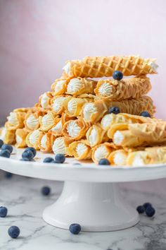 a white plate topped with waffles covered in blueberries next to another stack of waffles