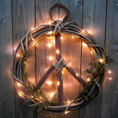 a peace sign made out of branches and lights on a wooden fence with string lights around it