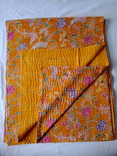 an orange and pink flowered cloth on a white sheet with a yellow border around it