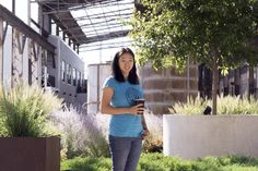 a woman standing in front of a building holding a cell phone and looking at the camera