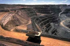 an aerial view of a large open pit in the middle of dirt and rocks with trucks on it