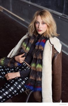 a woman sitting on a chair wearing a fur coat