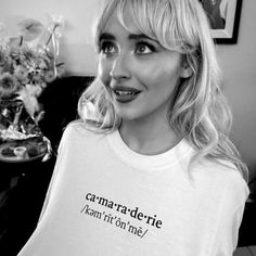 a black and white photo of a woman wearing a t - shirt that says camaraderie