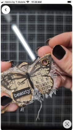 a person holding a small butterfly made out of newspaper strips and torn up with nail polish