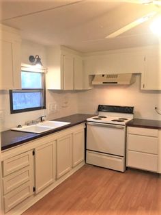 an empty kitchen with white cabinets and black counter tops