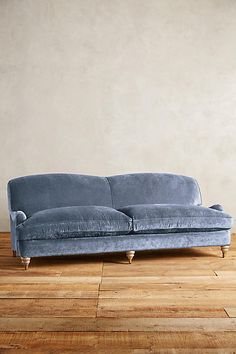 a green couch sitting on top of a hard wood floor next to a white wall