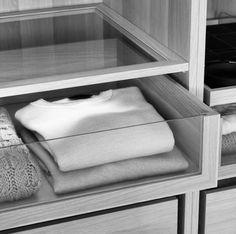 an open drawer with sweaters and other items in it on the shelf next to each other