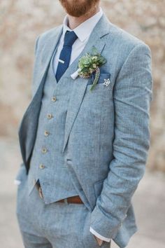 a man with a beard wearing a blue suit and flower boutonniere on his lapel